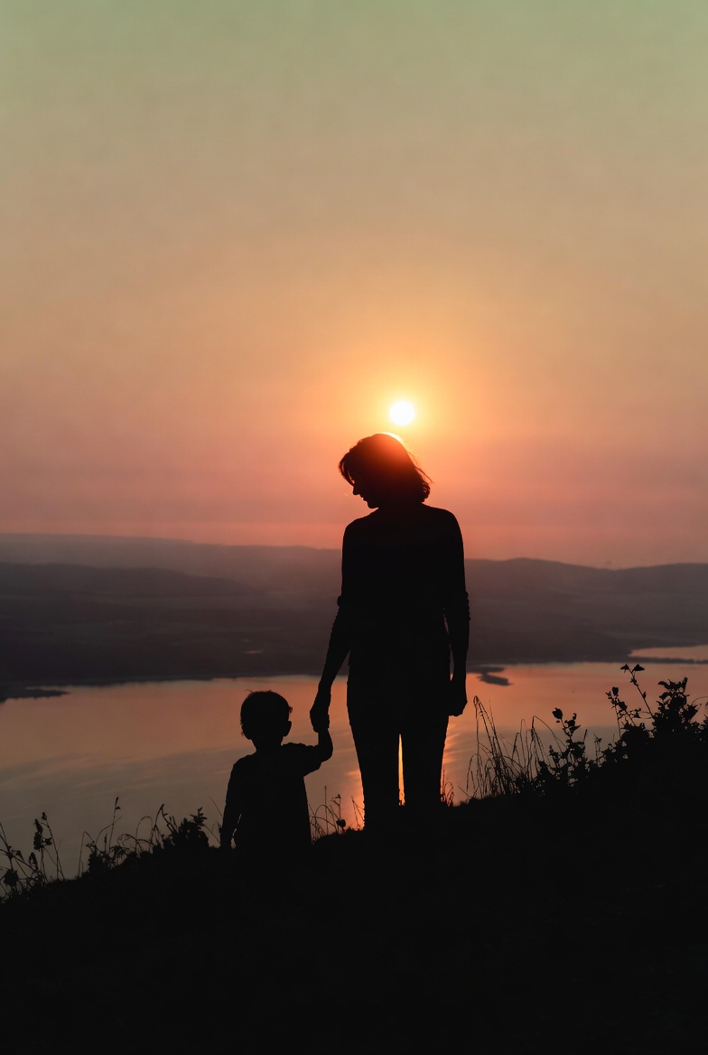 Silhouette of a mother and young child holding hands on a hill at sunrise, looking out over calm water – symbolizing hope, self-discovery, and new beginnings as a late-diagnosed ADHD mom