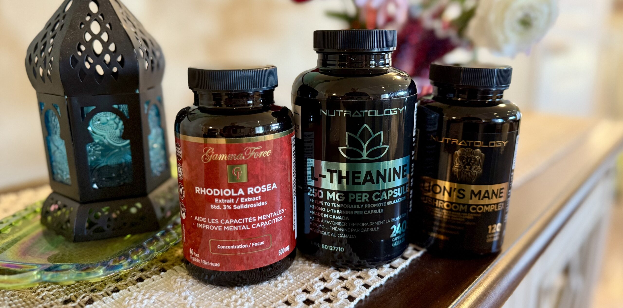 Bottles of supplements that are also ingredients found in Java Brain lined up on a wooden table top with flowers in the background