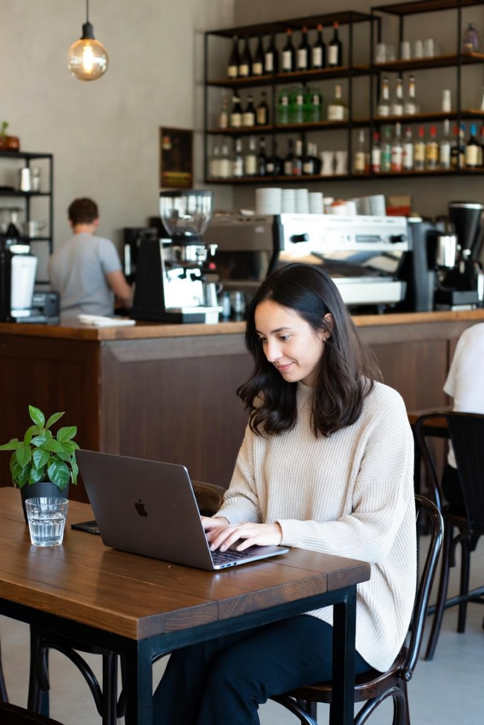 Woman with dark hair working on a laptop in a cozy cafe setting – representing focused time management and productivity for adults with ADHD